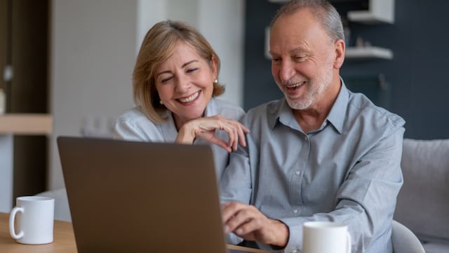 Älteres Paar vor einem aufgeklappten Laptop macht online den Fördermittelcheck