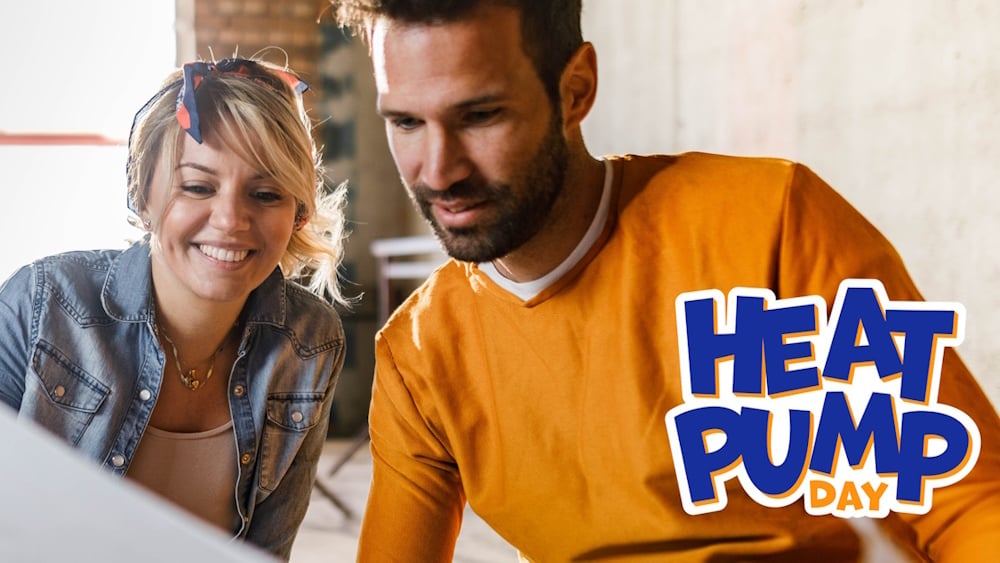 Frau und Mann sitzen lächelnd nebeneinander, unten rechts ist das Heat-Pump-Day-Logo zu sehen