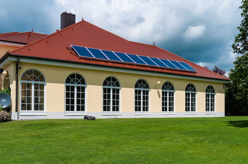 Ein Haus auf der grünen Wiese mit einer Solaranlage auf dem Dach