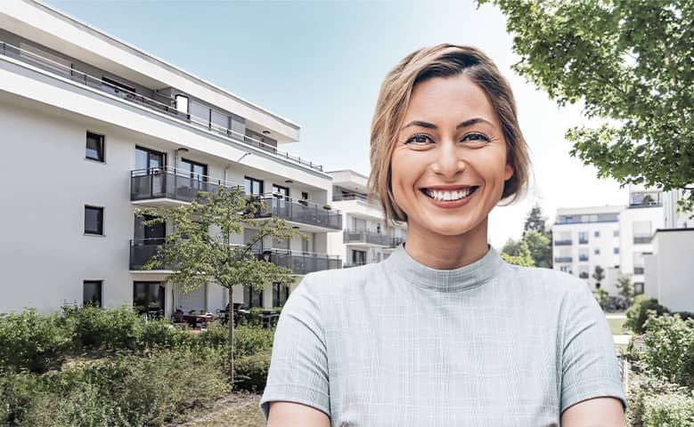 Planerin vor Apartment-Gebäude mit Grünanlage