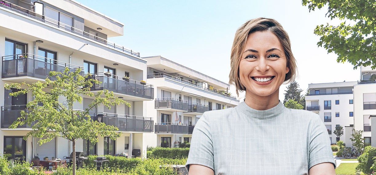 Planerin vor Apartment-Gebäude mit Grünanlage