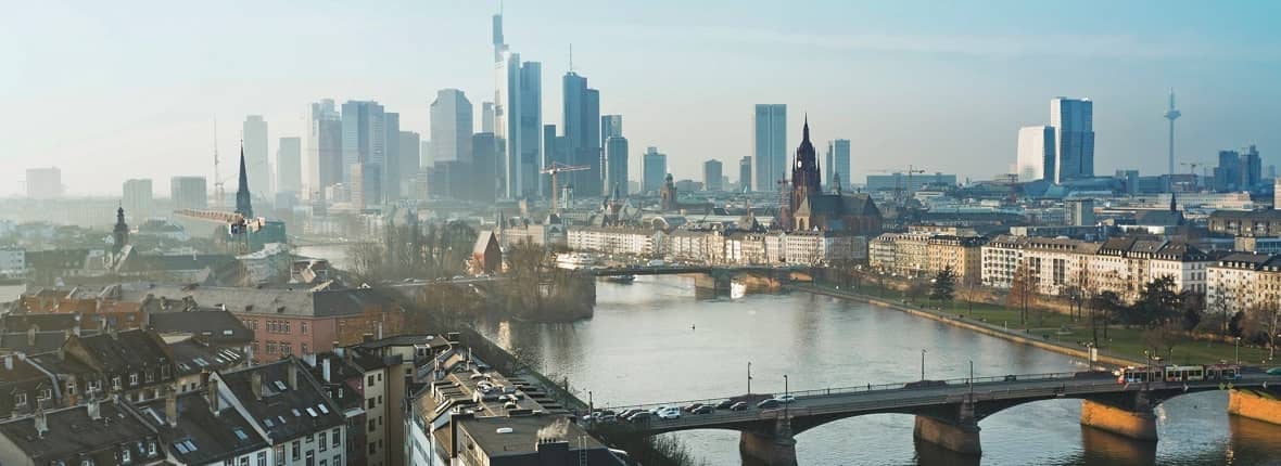 Großstadt-Skyline mit alten Häusern und Brücke über einen Fluss und Hochhäusern im Hintergrund