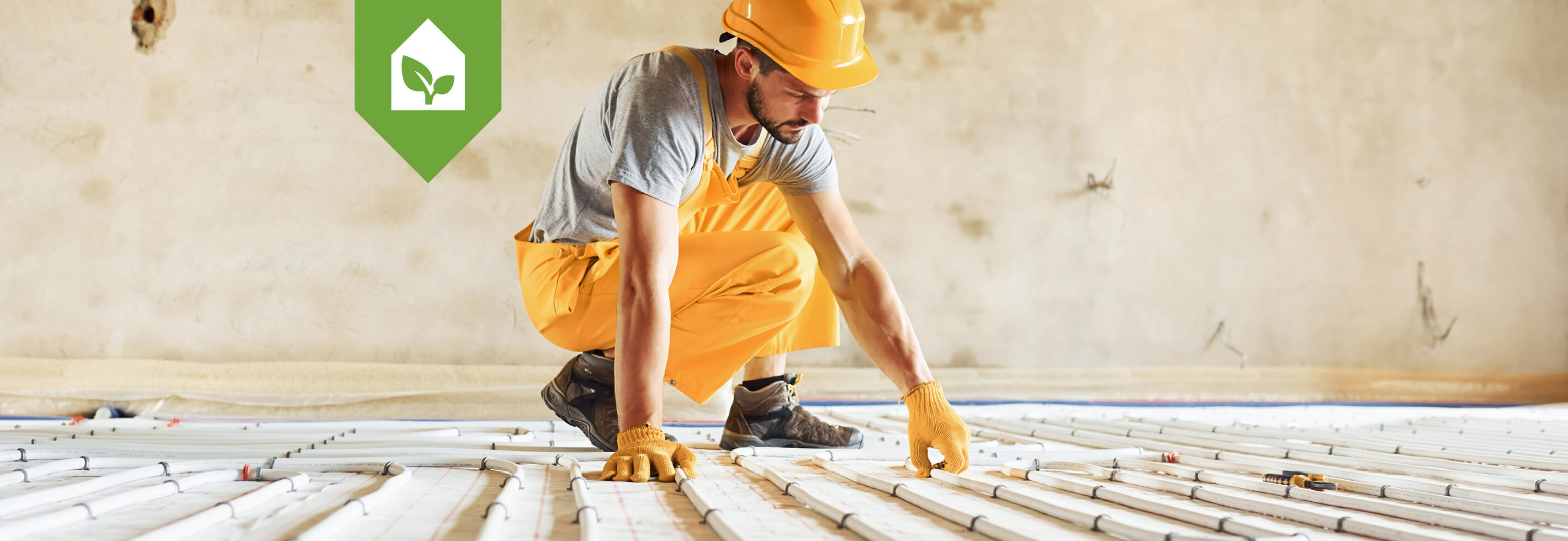 Duurzaam wonen - Remeha - Een close-up van een vloerverwarmingssysteem met witte leidingen die in een zigzagpatroon over een geïsoleerde ondergrond zijn gelegd.