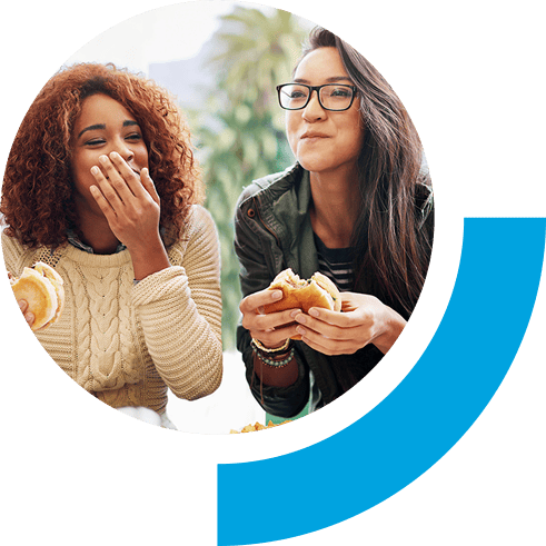 Two friends sitting and laughing together while holding burgers