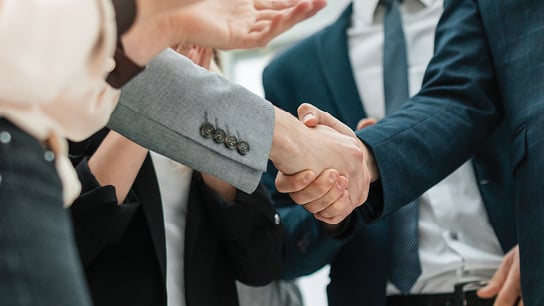 Business professionals engaging in a handshake during a meeting, symbolizing agreement and collaboration.