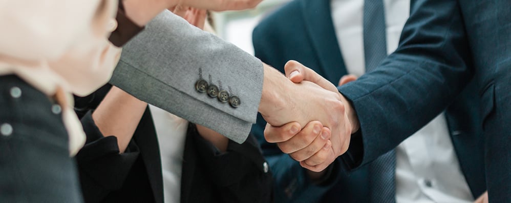 Business professionals engaging in a handshake during a meeting, symbolizing agreement and collaboration.