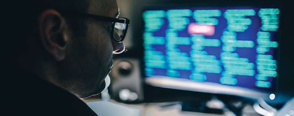Man focusing on computer screens with programming code visible