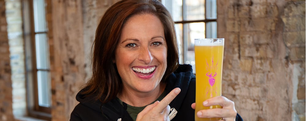 Marney Gellner holding a pint of beer in a rustic building