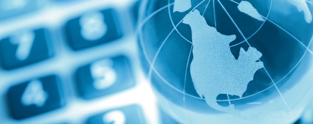 Blue-toned translucent globe showing North America, with a blurred calculator keypad in the background. Conveys themes of global finance and technology.