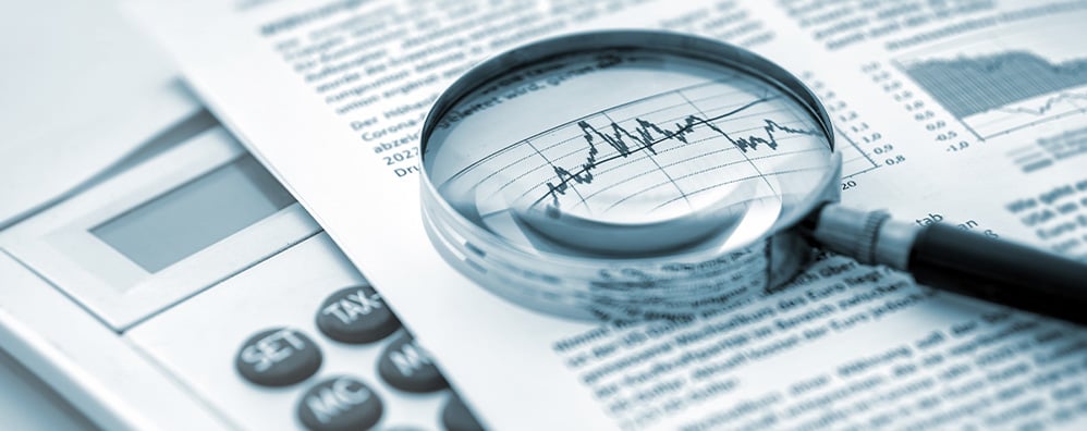 Magnifying glass on top of a paper report zooming into a graph.
