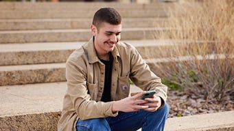 Person sitting outside on their phone