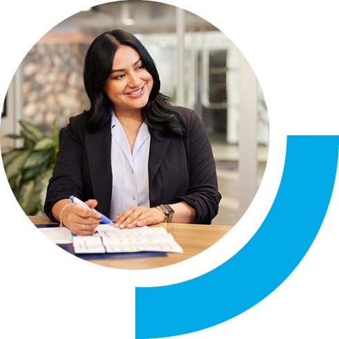 Bell employee smiling while sitting down with pen in hand on top of papers.