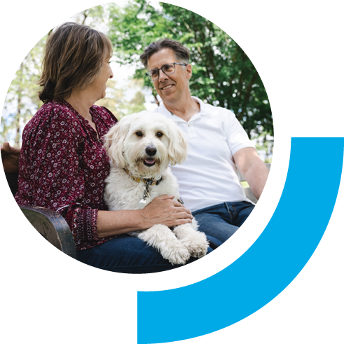 Elder couple sitting down on a bench outside on a sunny day with family dog
