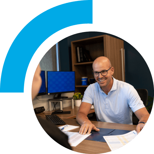 A man in an office setting smiling and showing papers to a customer