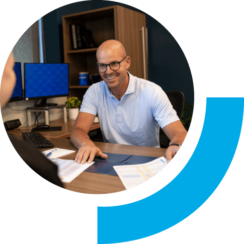 A man in an office setting smiling and showing papers to a customer