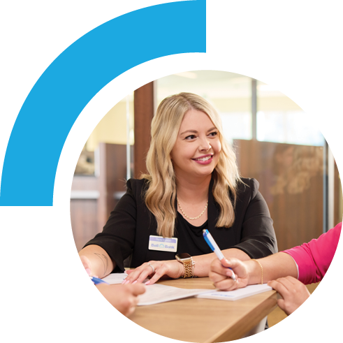 Bell employee sitting in a business team setting. All members have pens and paper and the employee pictured is seen smiling.