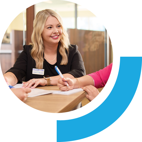 Bell employee sitting in a business team setting. All members have pens and paper and the employee pictured is seen smiling.