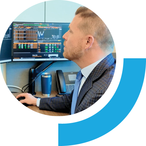 Corporate man at desk looking at computer screen with graphs and numbers.