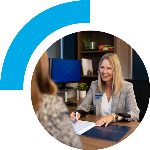 A woman in an office setting smiling and showing papers to a customer