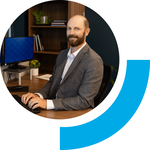 A man working in an office setting smiling while typing on a keyboard