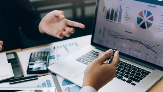 Hands pointing at a graph on a laptop