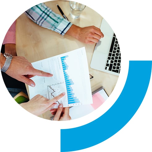 Team analyzing graph on desk with laptop open