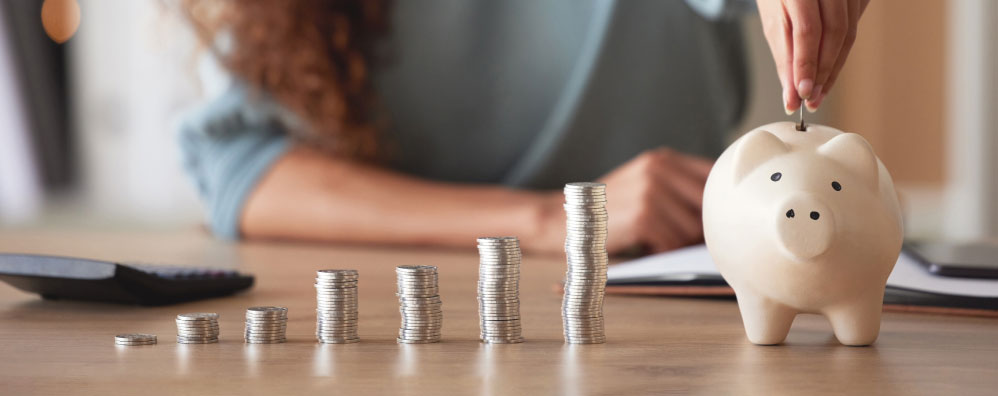 Person putting coins in a piggy bank