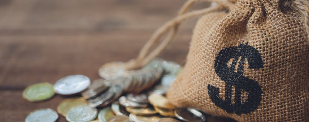 Brown bag of coins with dollar sign sits on top of coins