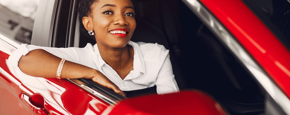 Smiling woman sitting in a car and leaning out the window.