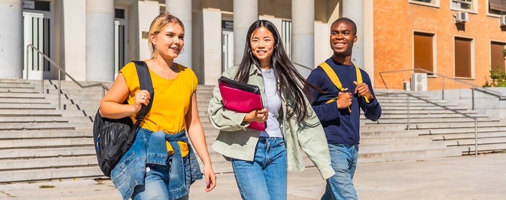 Three students walking with backpacks and smiling