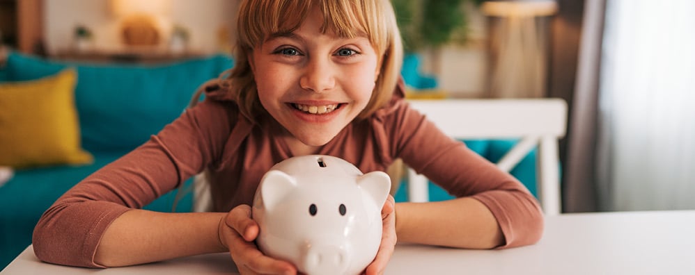 Girl smiling while holding a piggy bank