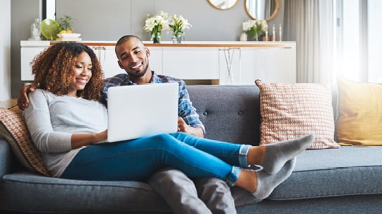 A couple on the couch on a laptop