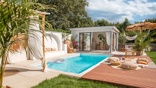 A backyard with a pool and pool house