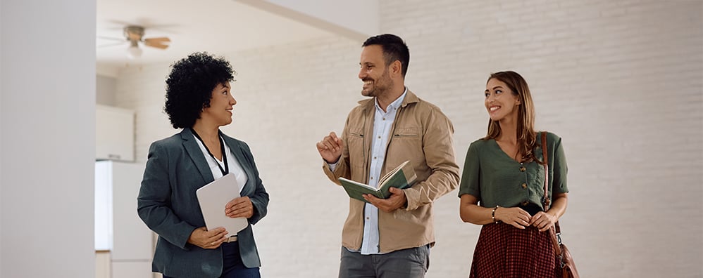 A couple walking through an open house with a phone or notepad.