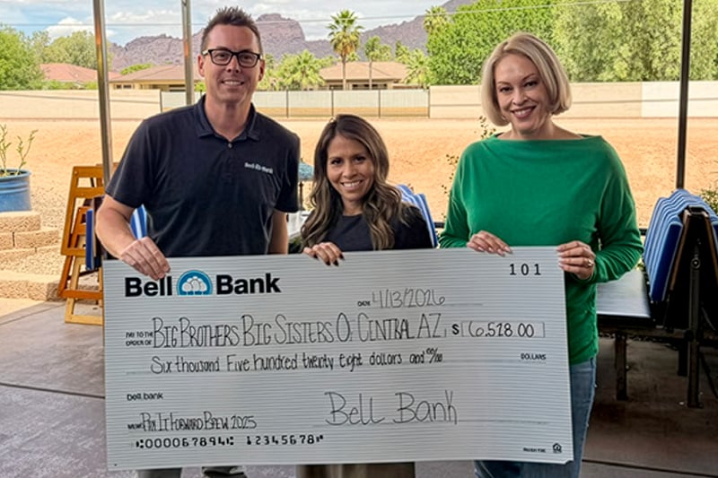 Three people holding a pay it forward check