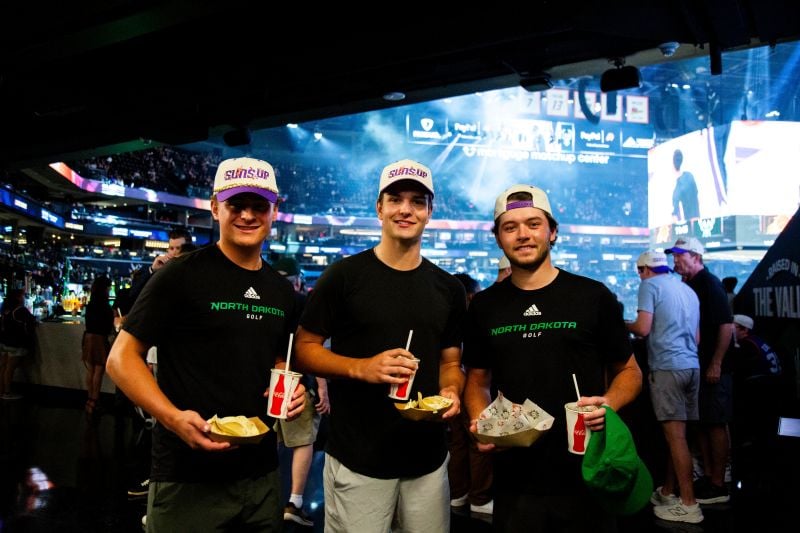 Three people smiling and holding food