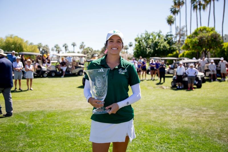 Golfer holding trophy and smiling