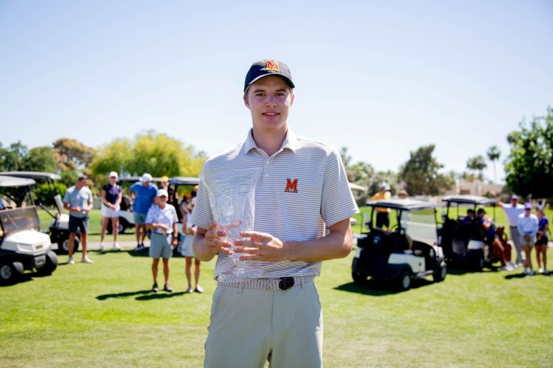 Golfer holding a trophy and smiling