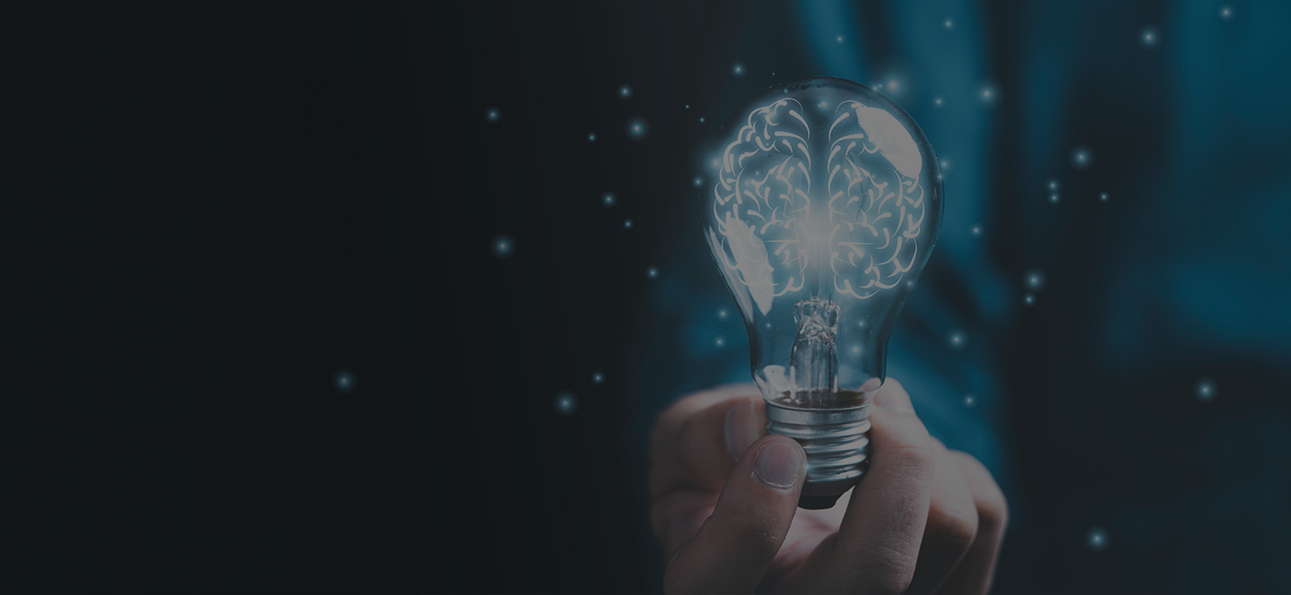 Hand holding a glowing light bulb with a stylized brain inside, symbolizing artificial intelligence, innovation, and intellectual property concepts such as AI patents or trade secrets.
