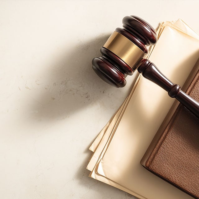 Wooden gavel resting on a leather law book and stacked legal documents on marble — courtroom justice theme, judgment, authority and legal concept background