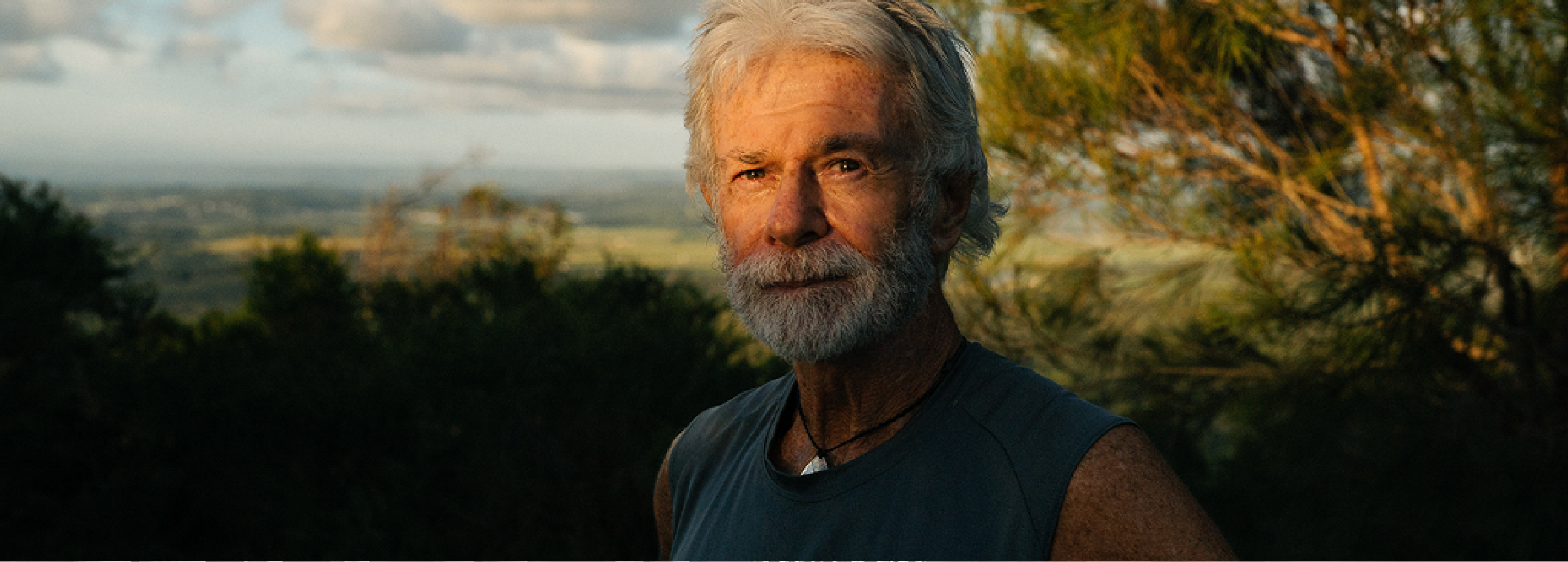 a photo of a man staring into the camera with the sun setting on his face