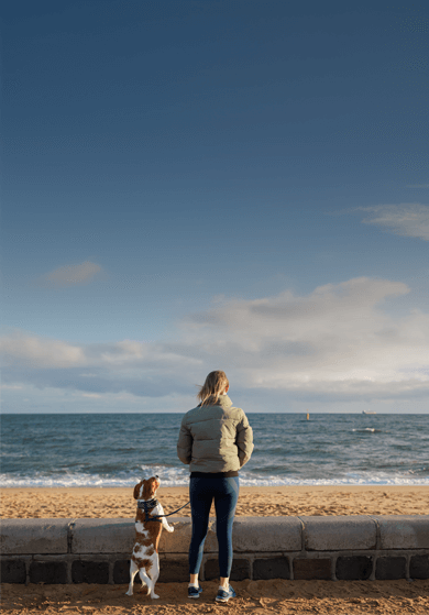 Woman walking dog on a beach