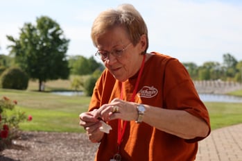 An elderly lady participating in raising butterflies at Birchaven Village, a senior living community.