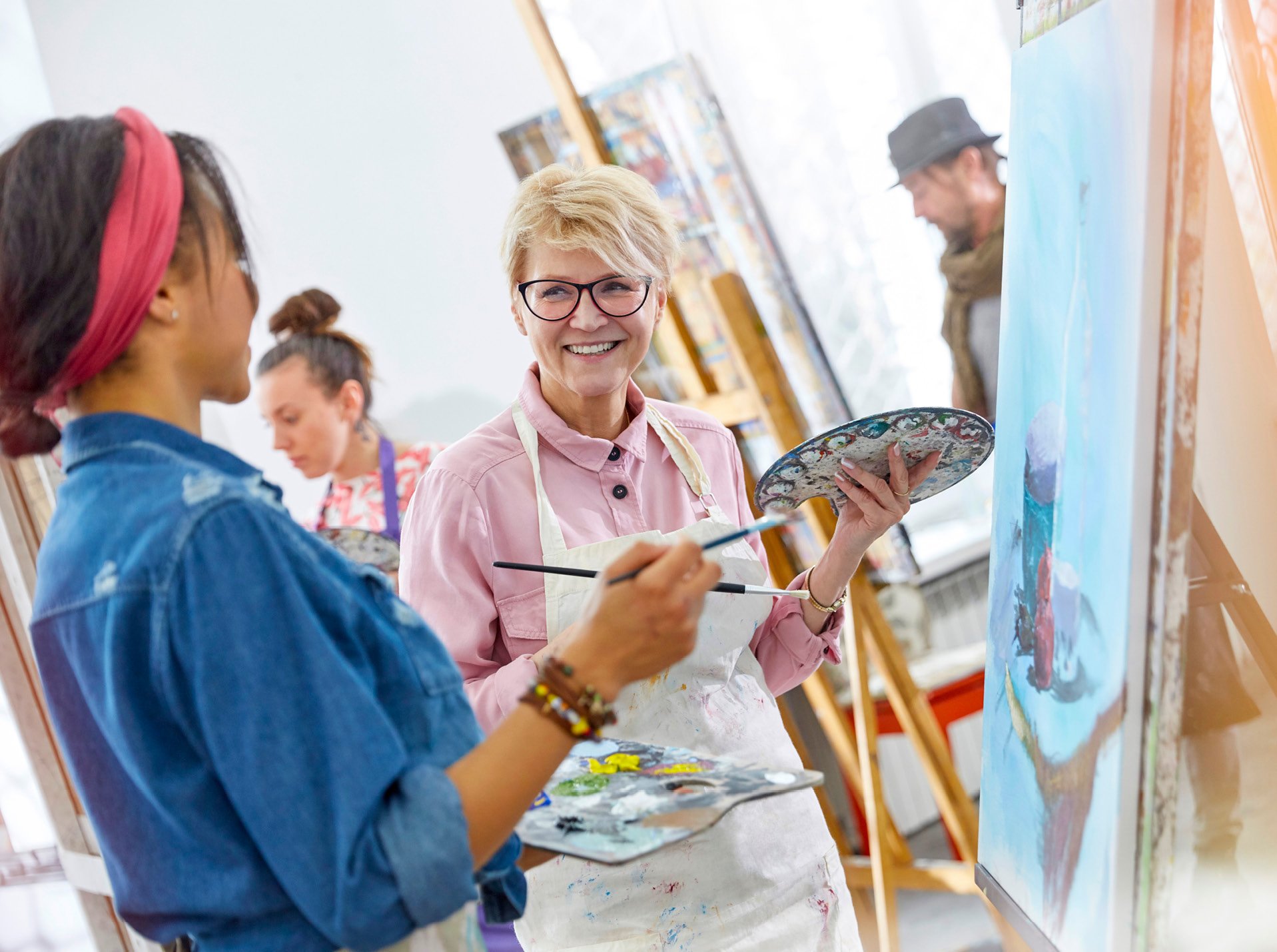 Two women conversing while taking a painting class