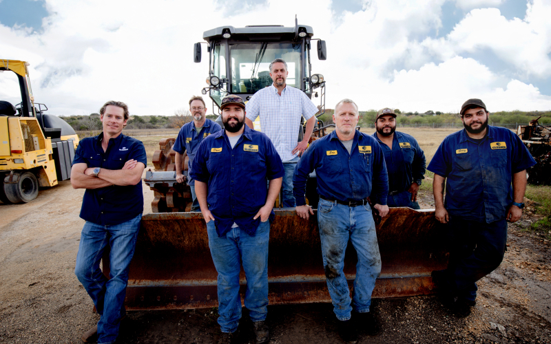 Closner equipment team poses for a picture in front of a tractor.