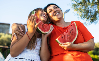 Mom and daughter eating a slice of watermelon on a bright summer day. 