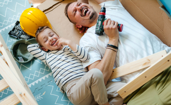 Dad holding a drill, working on a home improvement project and laughing with his son.