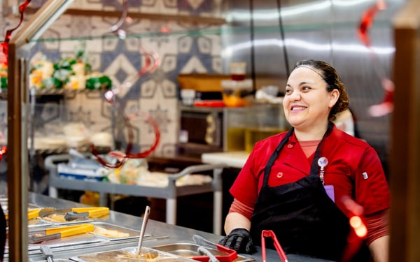 Smiling Supermercado Morelos employee behind the deli counter