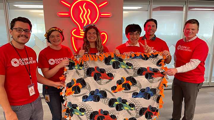 Bank of Oklahoma volunteers holding blankets they made.