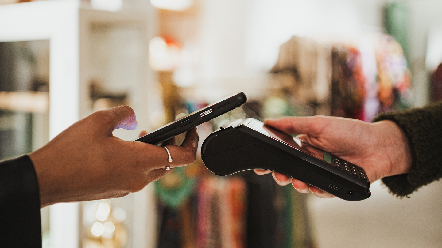 Primer plano de una mujer pagando con su teléfono